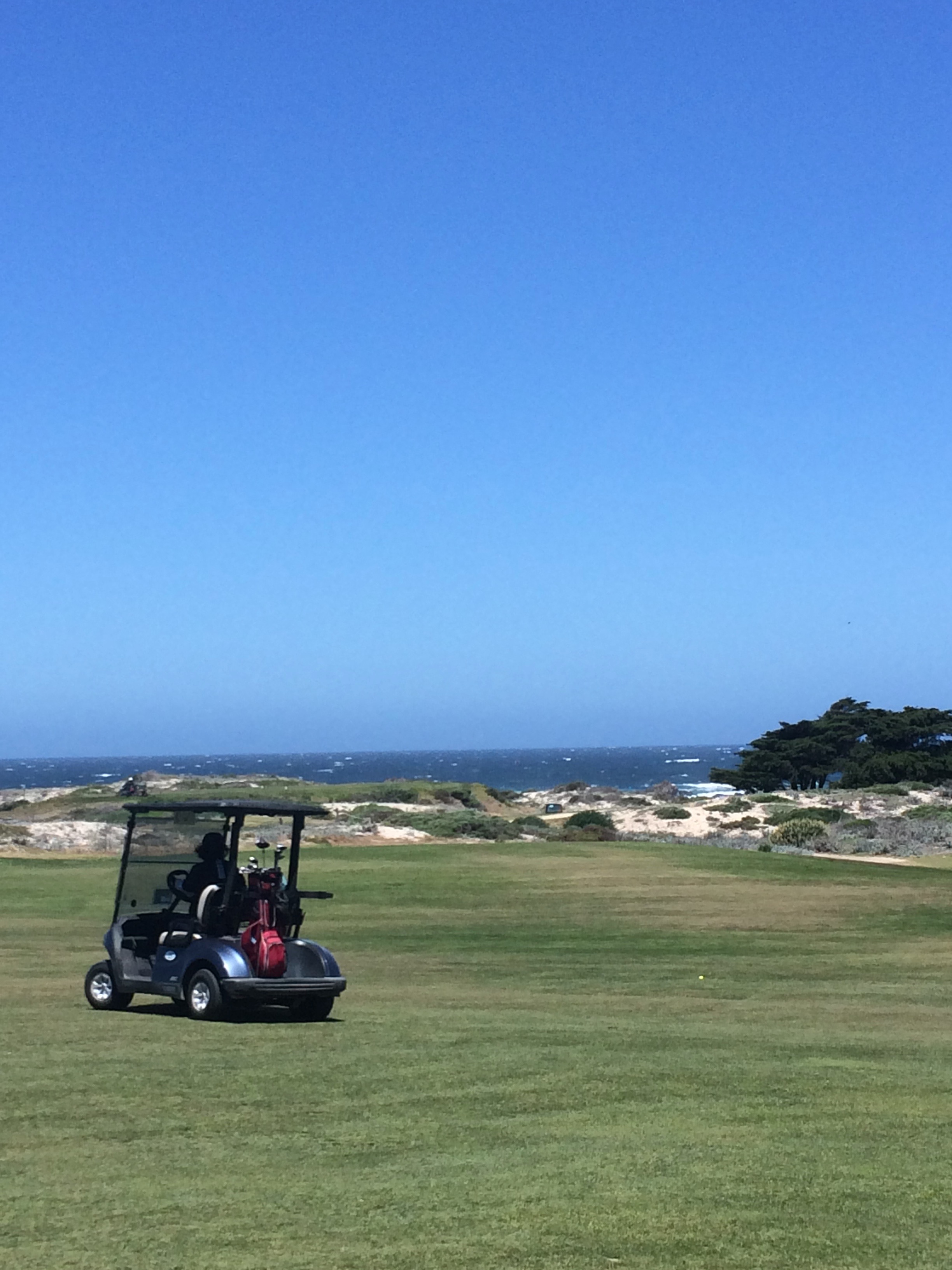 Image of golf cart on fairway, ocean in the background